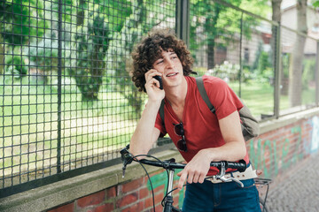 Wall Mural - Young man with bicycle on the phone