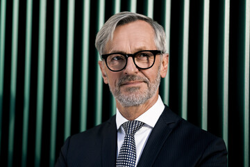 Wall Mural - Portrait of grey-haired businessman in front of green wall