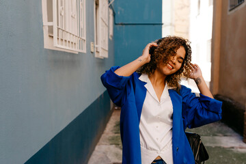 Wall Mural - Portrait of smiling woman listening to music with headphones