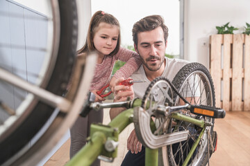 Wall Mural - Young man and little girl repairing bicycle together