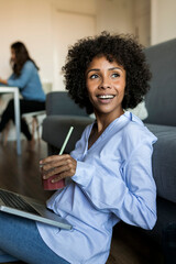 Wall Mural - Happy woman with soft drink sitting on floor using laptop