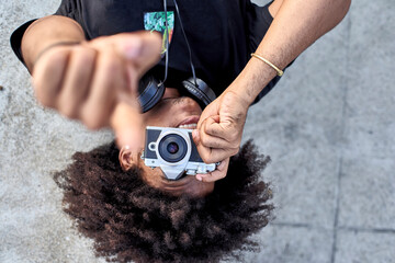 Poster - Young man laying on wall and taking pictures with his camera and pointing with his finger