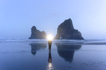 Wall Mural - Female tourist enjoying on Wharariki beach with iconic rocky mountain in archway island at New Zealand