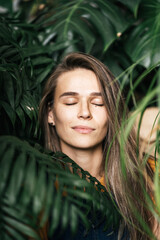 Portrait of a young woman with closed eyes amidst green plants