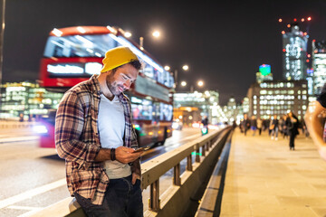 Wall Mural - UK, London, smiling man using phone at the street in the city at night