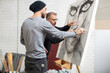 © tunedin - Artist discussing drawing with man in studio