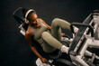 © Dusan Petkovic - Top view of a muscular fit black sportswoman practicing legs on a leg press machine while listening music.