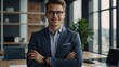 © muqadas - Head shot smiling confident young businessman executive wearing glasses and suit standing in modern office room, happy successful entrepreneur employee intern with arms crossed looking at camera