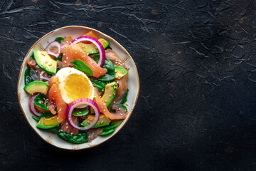 Wall Mural - Salmon, avocado and egg salad with fresh leaves and onions, overhead flat lay shot on a black slate background. Healthy diet, with copy space