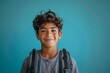 © Lux Images - Portrait of happy latin student boy with backpack smiling at camera, on isolated blue background. Back to school concept. Copy space
