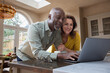 © ReeldealHD images - Happy senior couple at home booking a vacation using a laptop computer