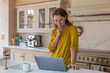 © ReeldealHD images - Happy senior woman at home in her kitchen using a laptop to look at his pension fund