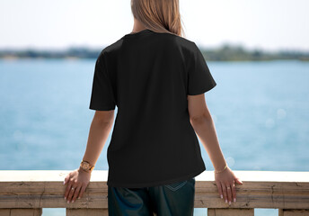 Wall Mural - Black texture T-shirt template on a blonde girl against the background of a river, back view, for design, branding, advertising.