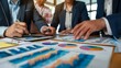 © Plaifah - Hands of business executives discussing financial charts and graphs during a meeting, symbolizing collaboration and decision-making