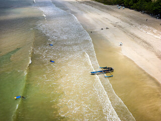 Canvas Print - Aerial view of surfers waiting for waves on a tropical sandy beach