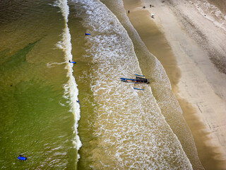 Wall Mural - Aerial view of surfers waiting for waves on a tropical sandy beach