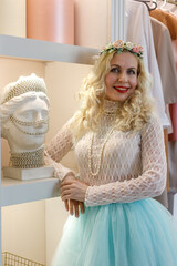 Fashion interior photo of a gorgeous middle-aged woman in elegant clothes. Young happy cheerful woman with long wavy blond hair standing in dressing room