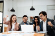 © aksonsat - Group of teamwork businesspeople are excited and happy to success and achievement on business financial and marketing after working on laptop and paperwork in office