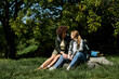 © Bliss - A young, multicultural lesbian couple sits together on a rock in the woods, enjoying a break from their hike.