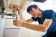 © Monkey Business - Male Plumber Fixing Leak In Domestic Bathroom Sink Or Basin