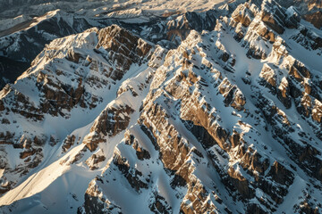 Wall Mural - Aerial view of snowy mountain peaks, highlighting the sharp contrasts between the white snow and the dark rocky outcrops. Focus on the clean lines and dramatic shadows.