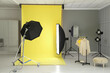 © New Africa - Yellow photo background, rack with clothes and professional lighting equipment in modern studio