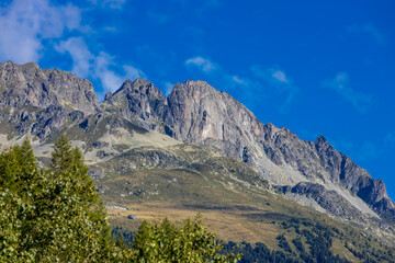 Tour du Montblanc beautiful mountain ladscapes of the Alps green valley, snow summit of Montblanc and rocky peaks of Aiguille du Midi in summer sunny weather blue sky, trekking and hiking in Chamonix