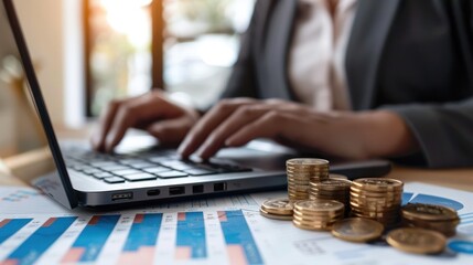 Wall Mural - A person is typing on a laptop computer with stack money coins