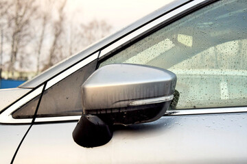 a side mirror of a modern car in raindrops