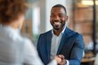 © Sandu - Man in blue suit smiling while handshaking woman in white shirt
