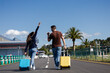 © Lucia PSV - excited couple with their suitcases walking on the road on the way to the airport to go on summer vacation
