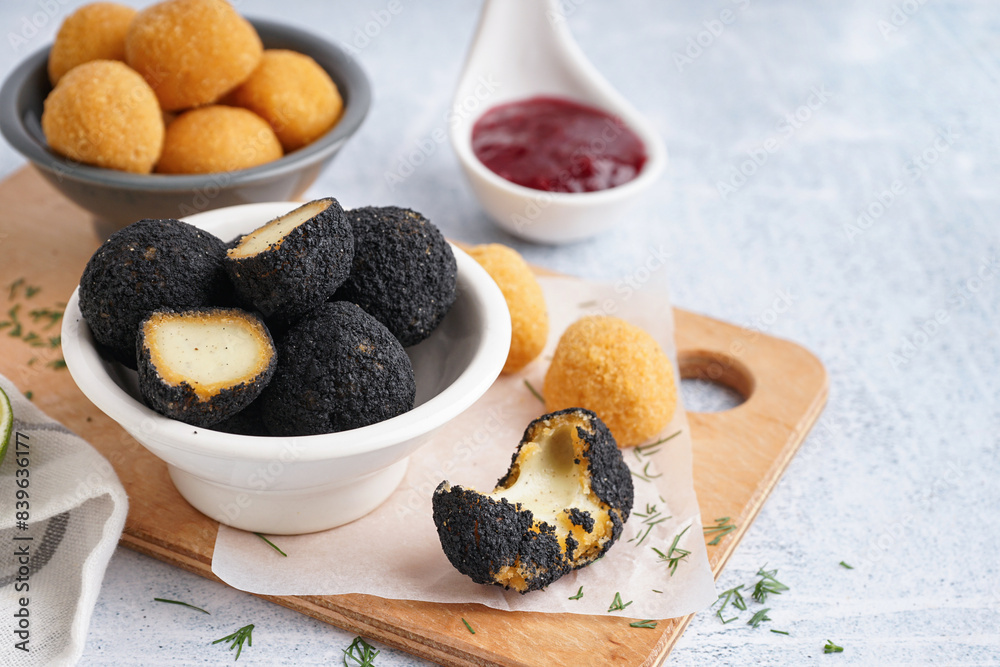 Bowls with different delicious fried mozzarella balls on light background, closeup