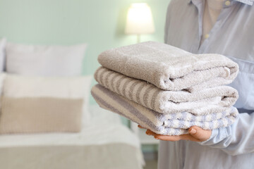 Wall Mural - Woman holding stack of clean soft towels in bedroom
