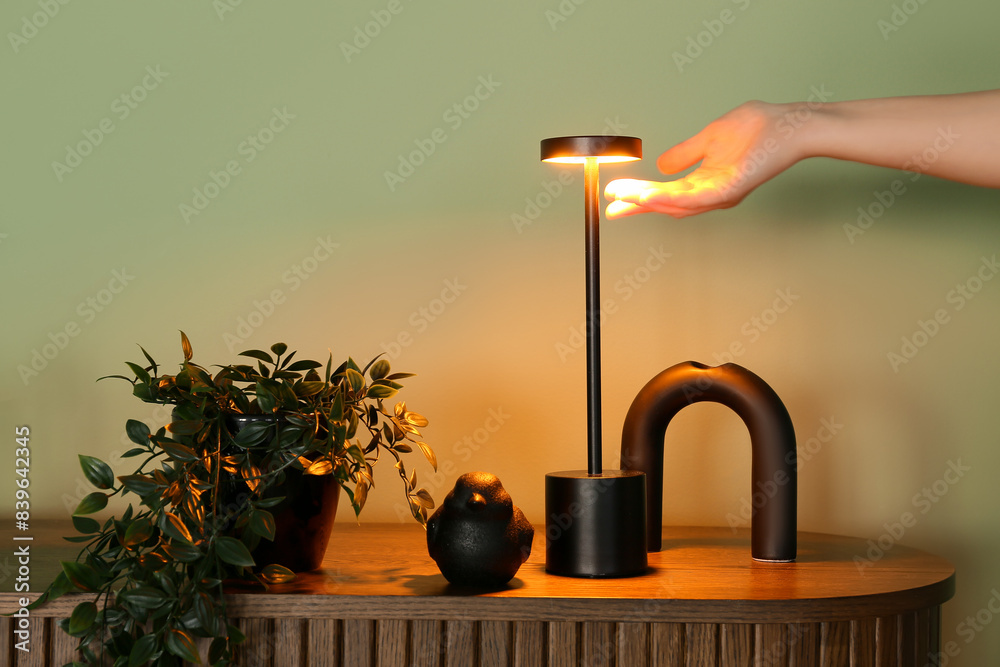 Woman pointing at glowing lamp near green wall