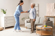 © Pixel-Shot - Physical therapist helping senior woman to walk at home