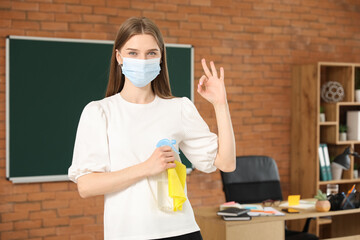 Canvas Print - Female teacher with medical mask and detergent showing OK in classroom