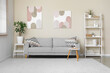 © Pixel-Shot - Interior of modern living room with grey sofa, shelving unit, coffee table and pictures on white wall