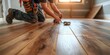 © Olena - Close up of man construction worker with pencil in hand drawing mark on laminate wooden plank. Male worker preparing laminate boards for floor installation in apartment under renovation.