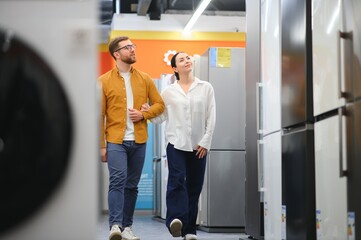 Wall Mural - family couple buying domestic refrigerator in supermarket