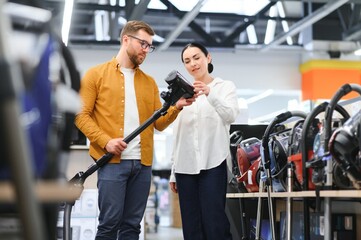 Young beautiful couple buying new vacuum cleaner at tech store. Having fun shopping time