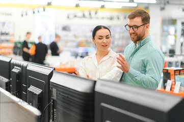 Wall Mural - Young couple shopping at tech store. Buying new tv set for their home