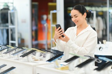 Wall Mural - Portrait of happy young woman buying a new smartphone in store. Shopping a new digital device