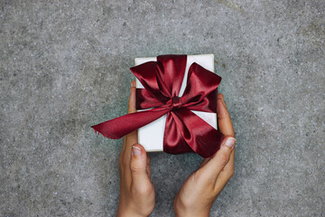 Wall Mural - hands woman holding a gift box with red ribbon  for holidays 