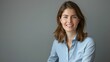 © Togrul - Smiling brunette businesswoman sitting against gray background. Confident female professional is wearing blue shirt. She is having brown hair. Copy space.
