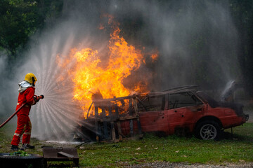 Wall Mural - Brave Firefighter in fire suit on rescue duty using water from hose extinguishing fighting with big crackle fire flames inside burning premises. Fireman spraying high pressure water fight a fire.