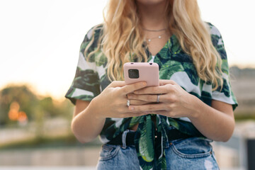 Unrecognizable blonde girl using smartphone outdoors