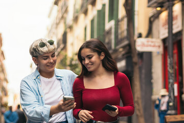 two teenager girls walking and watching something her mobiles