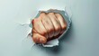 © Media Srock - A fist is shown through a hole in a wall. The fist is clenched and the hand is extended. Concept of strength and power