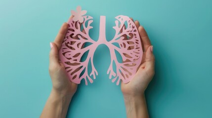Wall Mural - woman hands holding pink paper cut out lungs on blue background top view copy space,