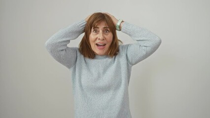 Wall Mural - Surprised and scared, a middle-aged woman, crazy expression etched on her face, stands in shock. hands on head, mouth agape, all isolated on a crisp, white background, she dons a cozy sweater.